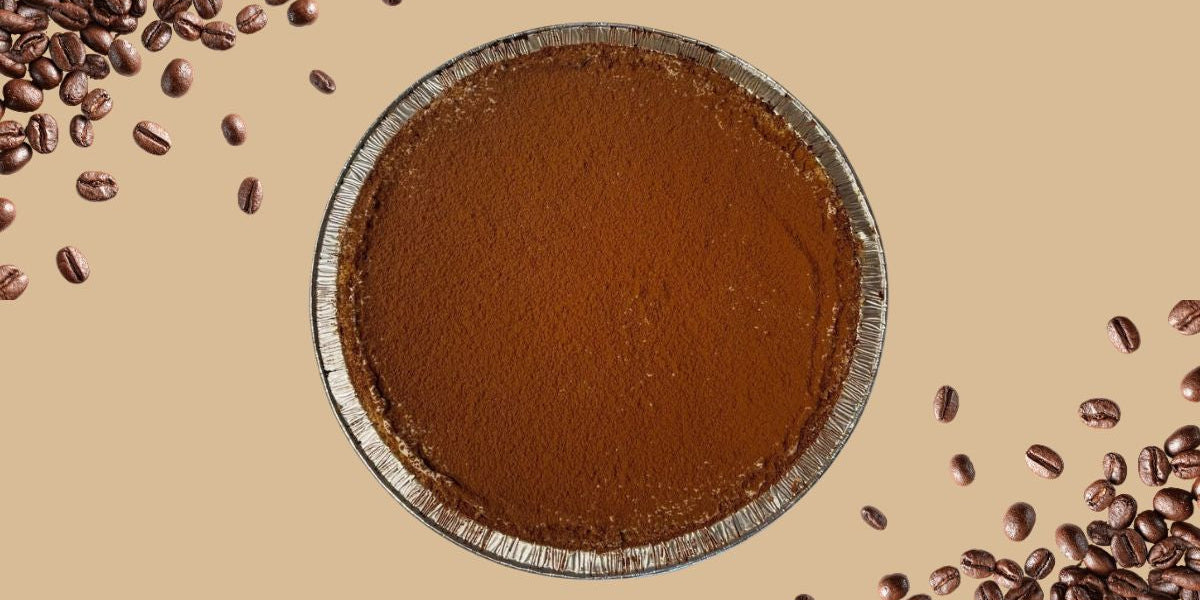 Cold brew tiramisu pie dusted with cocoa surrounded by coffee beans baking with cold brew