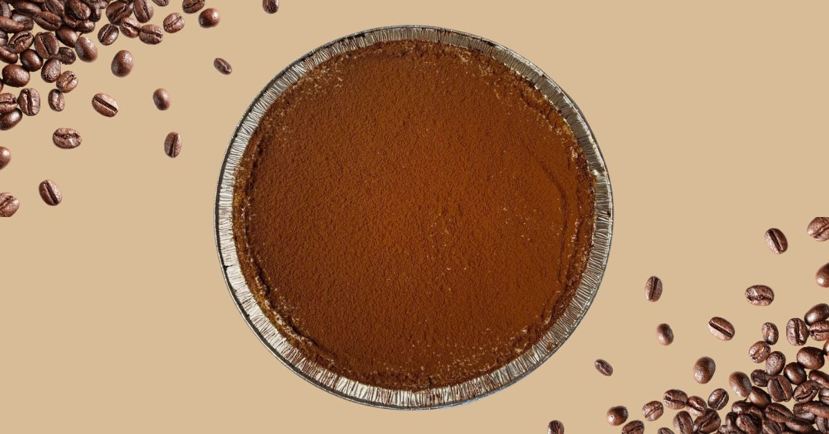 Cold brew tiramisu pie dusted with cocoa surrounded by coffee beans baking with cold brew