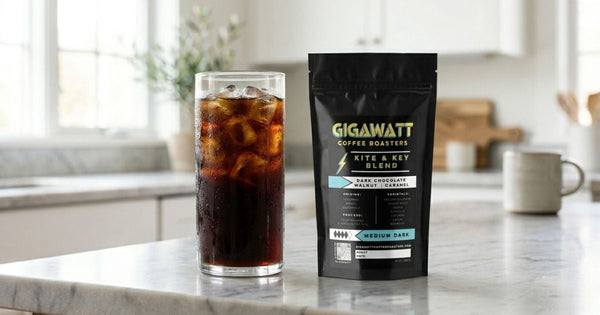 Glass of cold brew coffee with ice on a kitchen counter next to a bag of Gigawatt Coffee