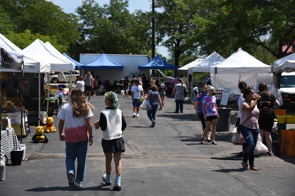 Shoppers browsing vendor booths at the Schaumburg Farmers Market at Trickster Cultural Center on a Friday morning