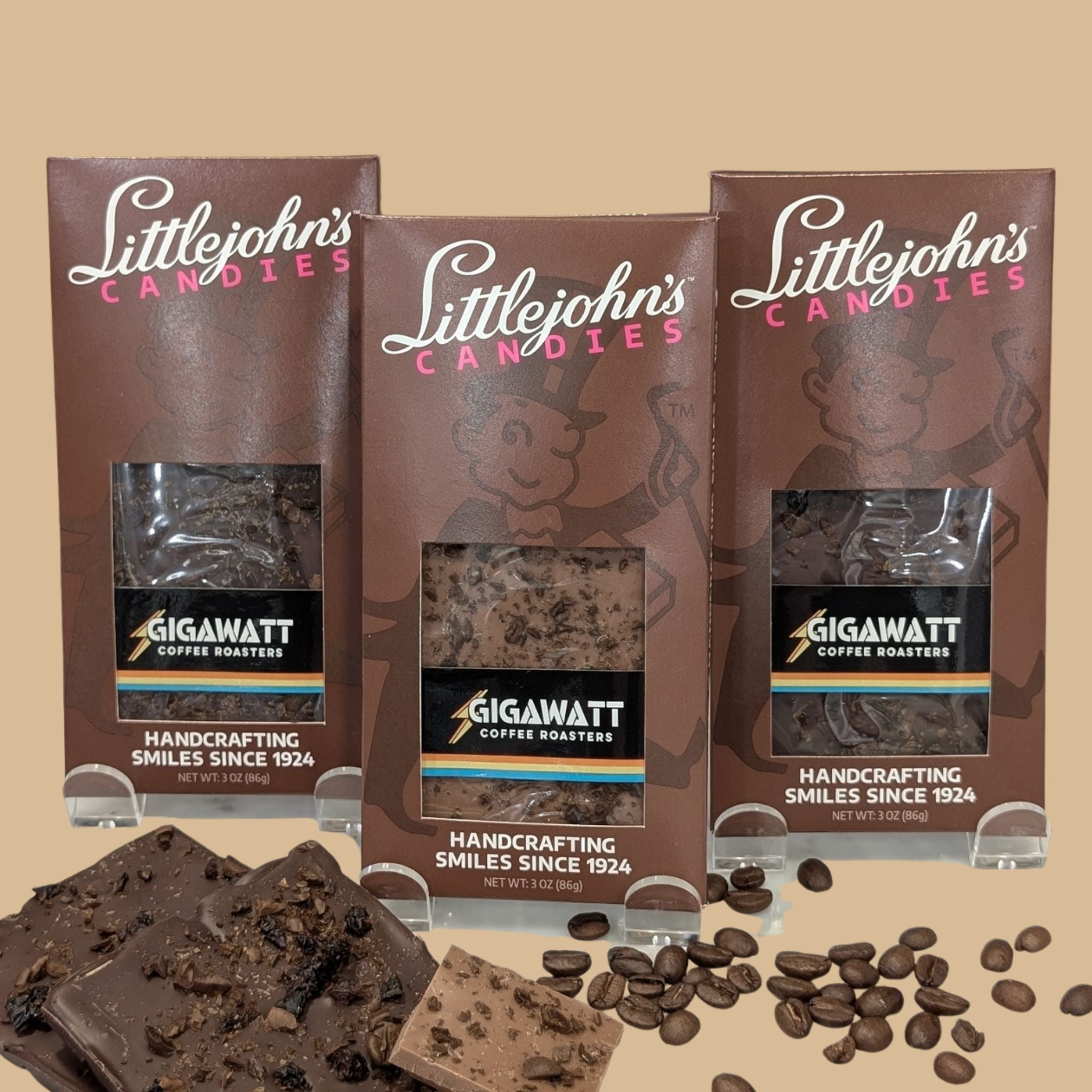 Coffee Chocolate Bar Collection 3-bar variety pack by Gigawatt Coffee Roasters and Littlejohn's Candies on a solid light brown background with chocolate and coffee beans on the surface