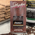 72% dark chocolate and cherry bar made with organic Honduran coffee by Gigawatt Coffee Roasters and Littlejohn's Candies on a surface with a chocolate and coffee beans