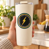 Hand holding a cream tumbler with the Gigawatt bolt circle coffee sticker in a sunny kitchen