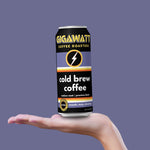 Gigawatt cold brew coffee can held in a hand against a purple background
