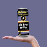 Gigawatt cold brew coffee can held in a hand against a purple background